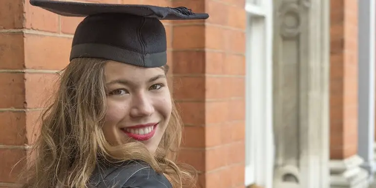 Smiling Female Graduate Posing in Black Cap and Gown